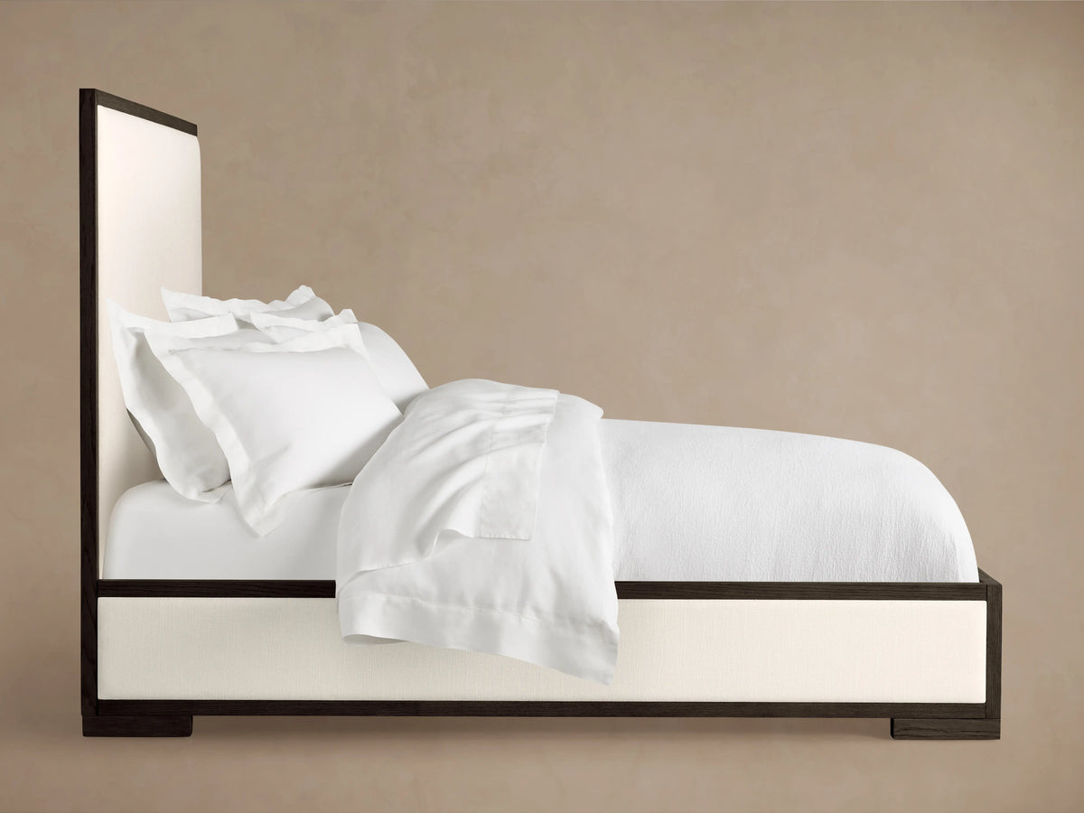 Darien Panel Bed with Low Footboard in side view; oak wood frame with white upholstered panels, white bedding, no box spring.