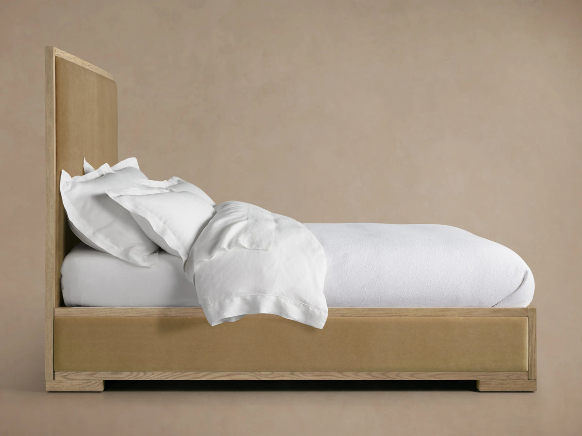 Darien Panel Bed with Low Footboard in oak with a hand-applied finish. Side view, white bedding slightly untucked.