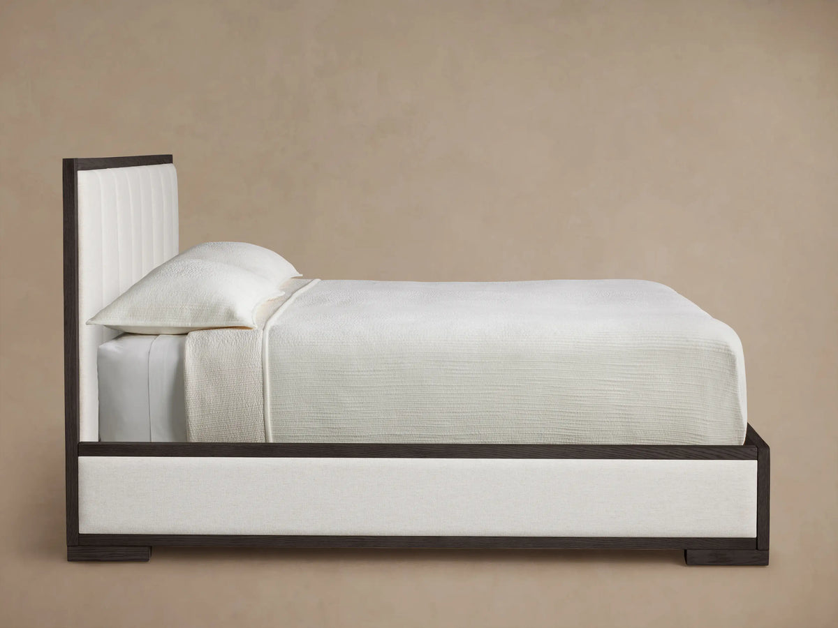 Close-up of Darien Channel-Stitched Panel Bed headboard, featuring cream channel-stitched fabric and dark oak wood frame.