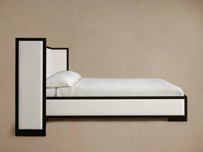 Close-up of Darien Extended Box-Tufted Shelter Bed headboard. Light, textured, box-tufted fabric bordered by a dark oak frame.