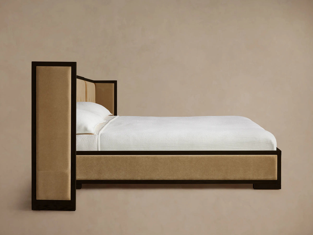 Angled close-up of Darien Extended Box-Tufted Shelter Bed headboard corner. Dark oak frame, light beige box-tufted upholstered panels.