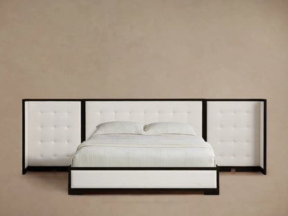 Darien Extended Box-Tufted Shelter Bed with white tufted headboard and side wings, dark wood frame, white bedding, on wood floor.
