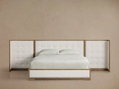 Darien Extended Box-Tufted Shelter Bed with white upholstered headboard & side panels, light oak frame, white bedding on wood floor.