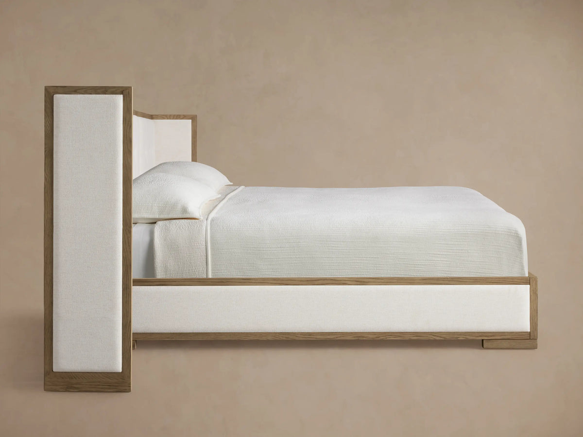 Close-up of Darien Extended Box-Tufted Shelter Bed showing light oak frame and textured off-white fabric upholstery.