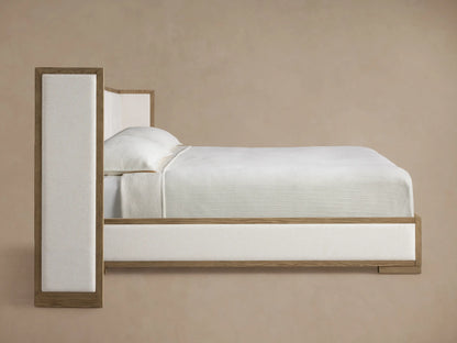 Close-up of Darien Extended Box-Tufted Shelter Bed with light brown oak frame and cream-colored tufted fabric upholstery.