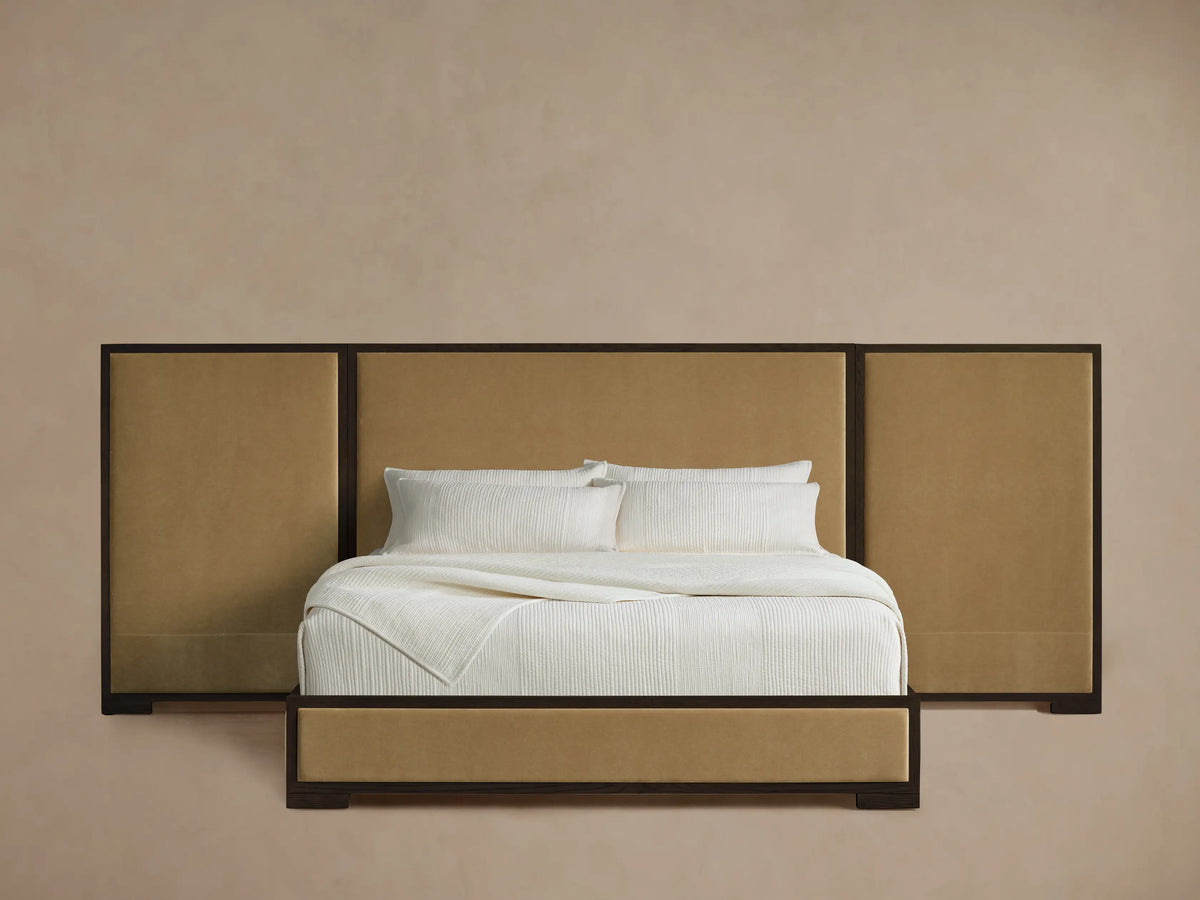 Darien Extended Panel Bed with tan upholstered panels & dark wood frame, made up with crisp white bedding on a wood floor.