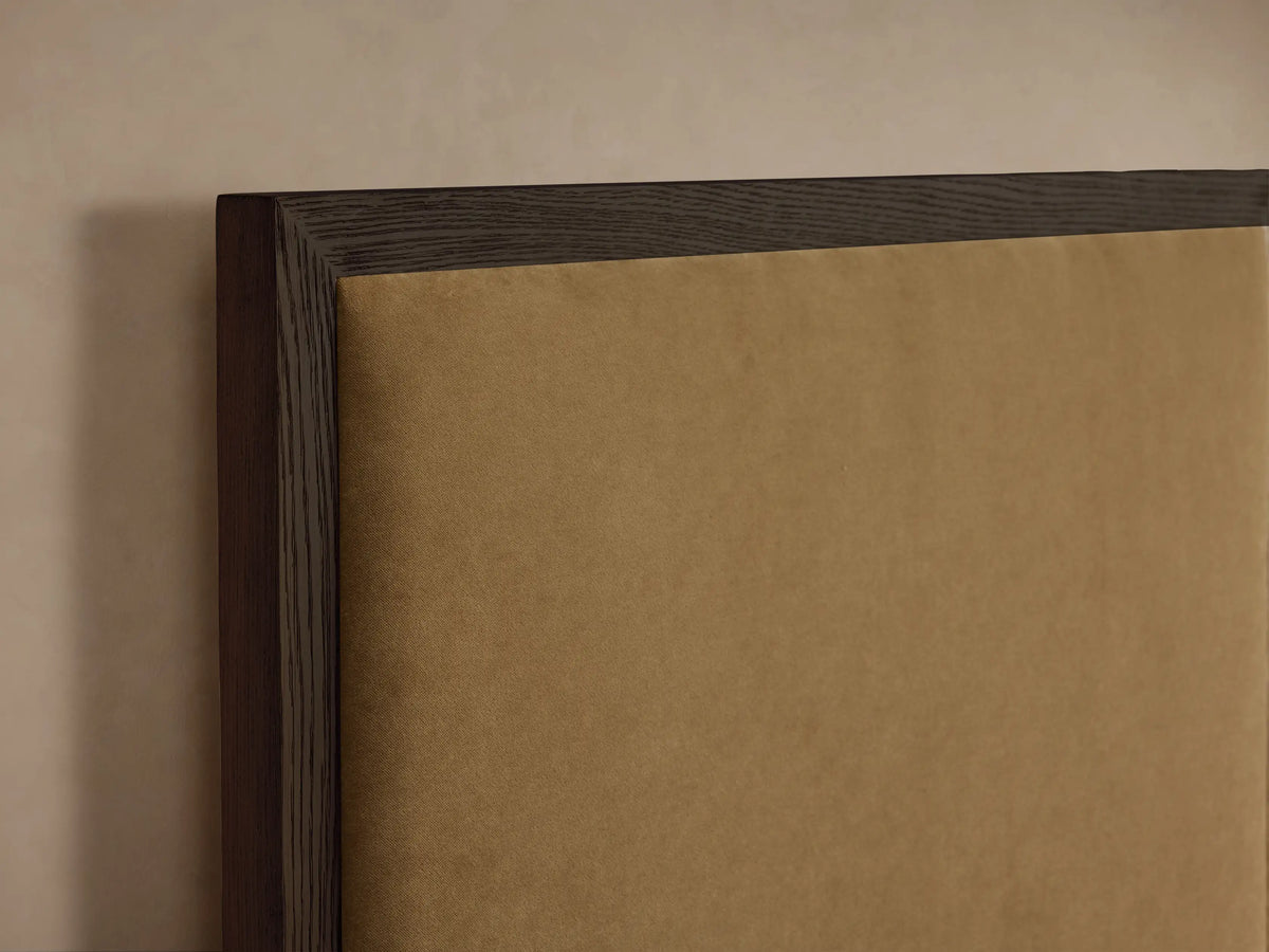 Darien Extended Panel Bed with a dark wood frame, camel upholstered panels, and white bedding, centered against a beige wall.