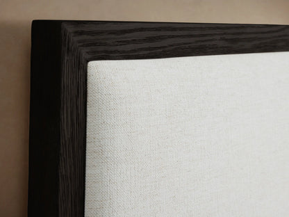Darien Extended Panel Bed with dark wood frame and white upholstered panels, shown with white bedding and a brown throw.