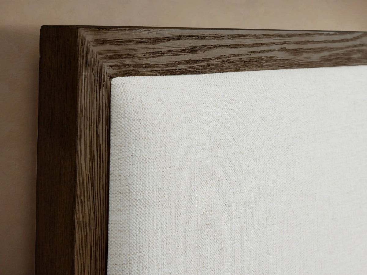 Front view of the Darien Extended Panel Bed featuring a brown oak frame and white upholstered panels, with white bedding and a brown throw.