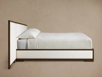 Close-up of the dark brown oak wood frame and light beige textured upholstered panel of the Darien Extended Panel Bed.
