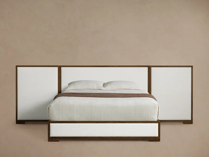 Front view of the Darien Extended Panel Bed with dark oak frame, white upholstered panels, white bedding, and brown throw.