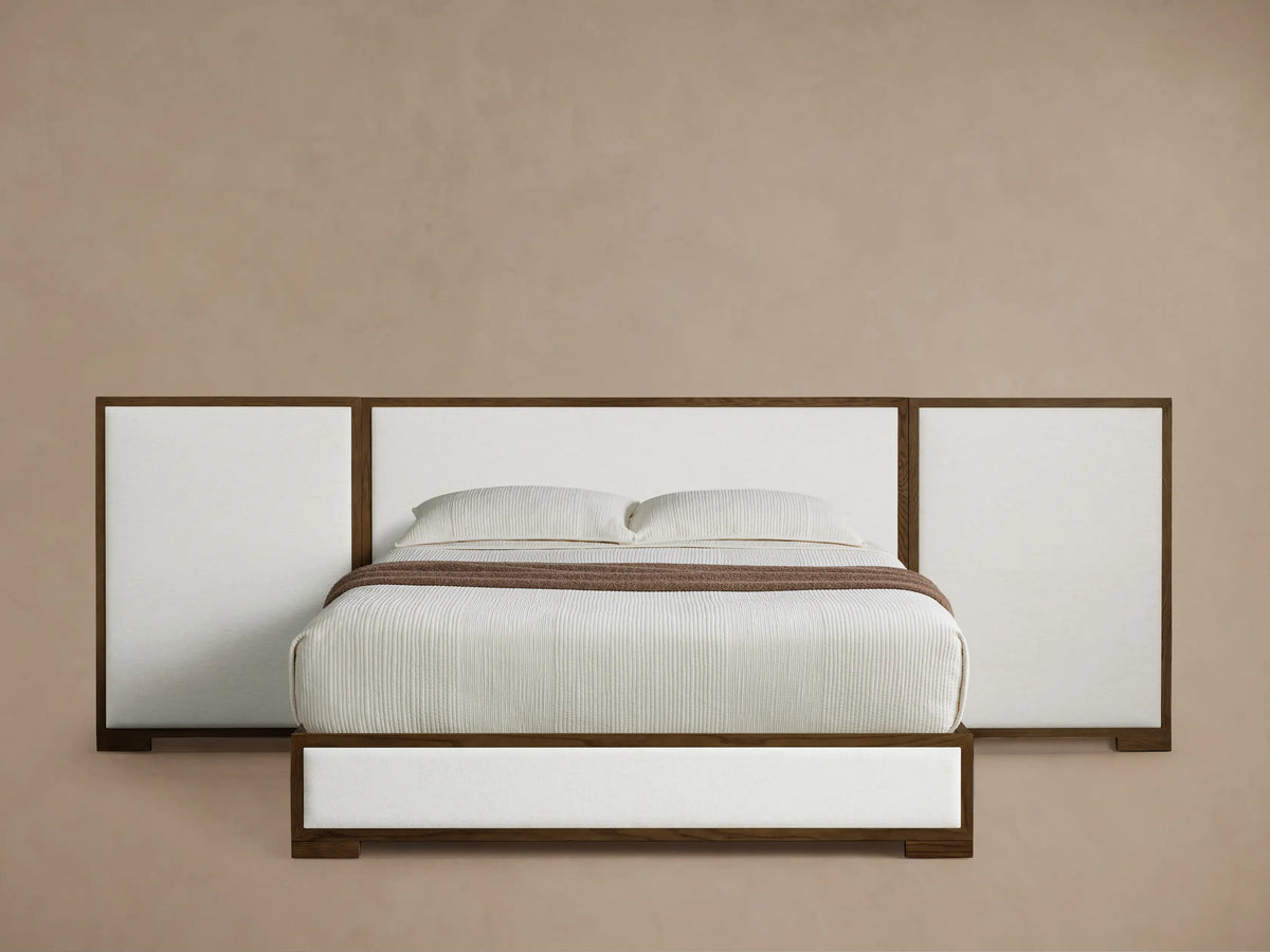Front view of the Darien Extended Panel Bed, with dark brown oak frame, white upholstered panels, white bedding and brown throw.
