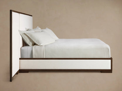 Front view of the Darien Extended Panel Bed with a dark oak frame, white upholstered panels, white bedding, and brown throw blanket.