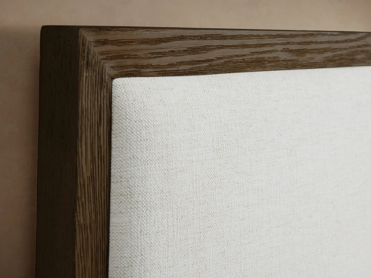 Side profile of the Darien Extended Panel Bed, featuring a dark oak frame, white upholstered headboard panels, and white bedding.
