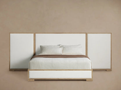 Darien Extended Panel Bed with light oak frame, white upholstered 3-panel headboard, white bedding, and a brown throw.