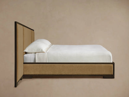 Close-up of Darien Extended Panel Bed headboard. Dark brown oak frame with visible grain, surrounding a tan upholstered panel.