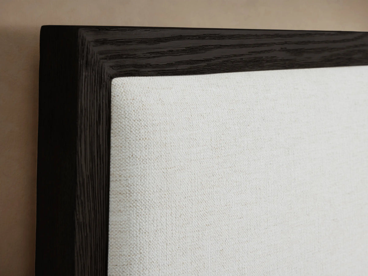 Darien Extended Panel Bed with dark oak frame and white upholstered extended headboard, styled with white bedding & brown throw.