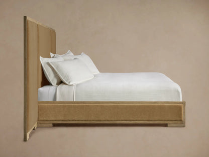 Darien Extended Panel Bed. Close-up of light oak frame with visible grain around a plush, tan upholstered headboard panel.