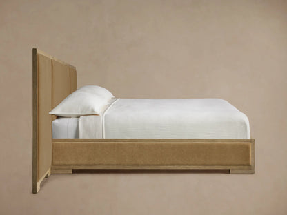 Close-up of Darien Extended Panel Bed's top right corner. Light oak frame with prominent grain around a tan upholstered panel.