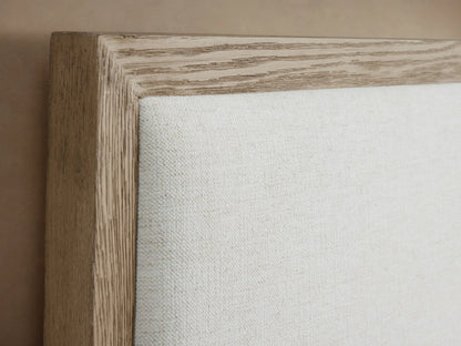 Darien Extended Panel Bed: light oak frame, white upholstered main headboard and two side panels, white bedding, brown throw.