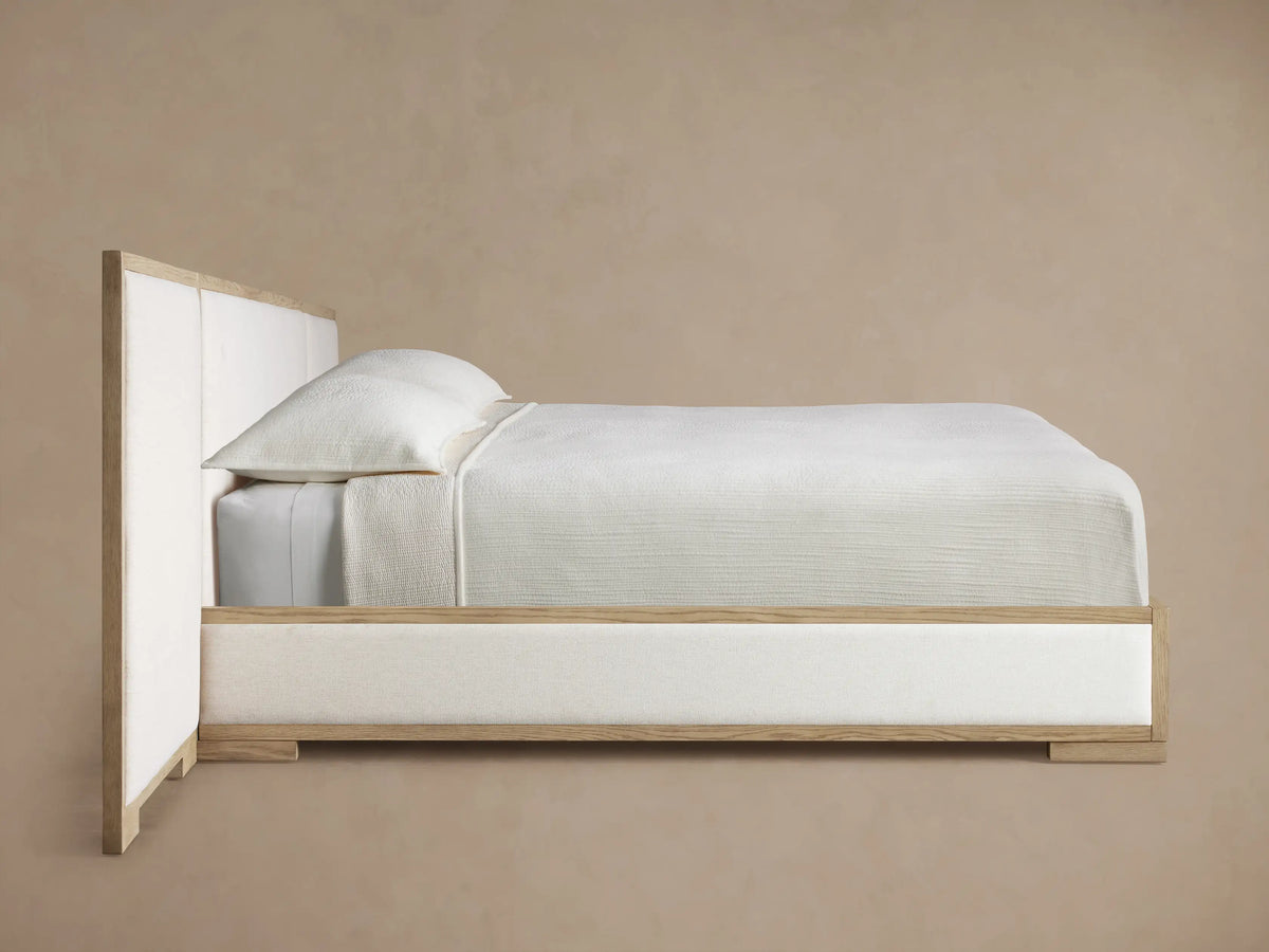 Close-up of Darien Extended Panel Bed headboard corner: light oak wood frame with grain texture, enclosing a cream fabric panel.