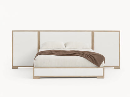 Darien Extended Panel Bed: light oak frame, white upholstered extended headboard & base, white bedding, brown throw on wood floor.