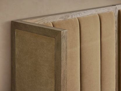 Darien extended shelter bed. Wide oak frame with tan channel-stitched upholstered panels, white bedding, against a beige wall.