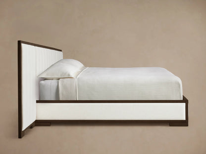 Side profile of the Darien Extended Channel-Stitched Panel Bed, dark brown oak frame, white channel-stitched panels, and white bedding.
