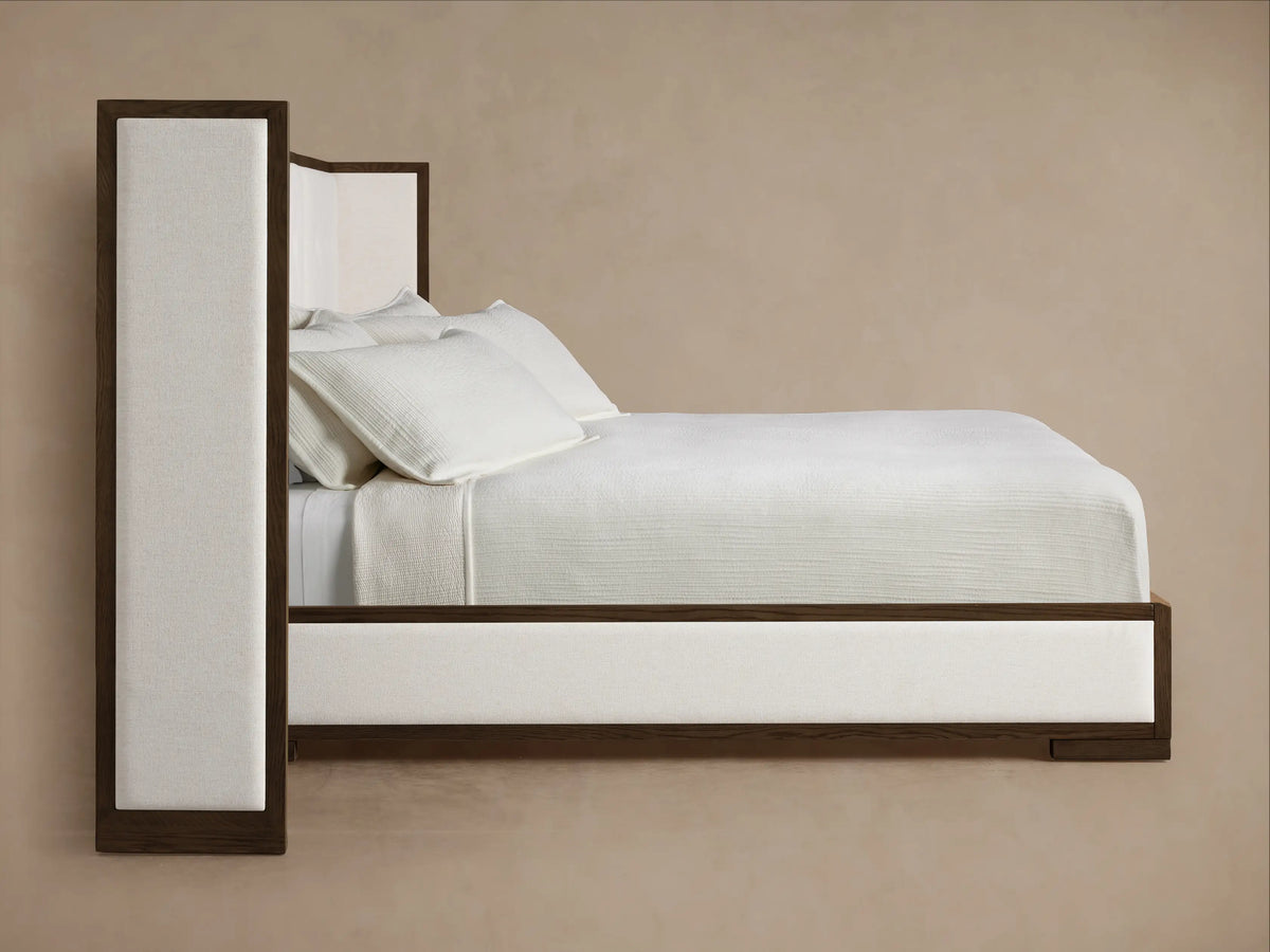 Front view of the Darien Extended Box-Tufted Shelter Bed with dark wood frame and white box-tufted upholstery. It features white bedding.