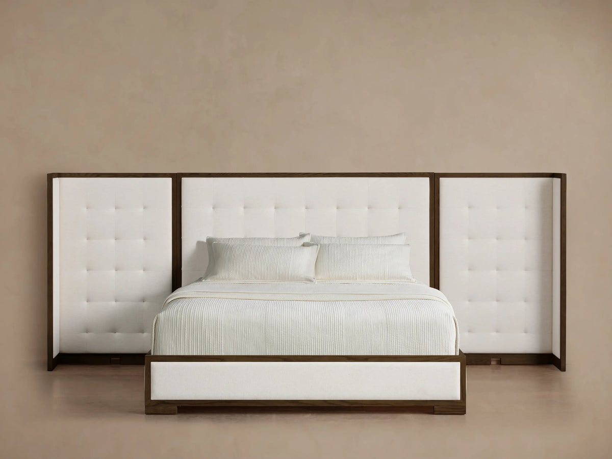 Front view of the Darien Extended Box-Tufted Shelter Bed with white box-tufted upholstery, dark wood frame, and white bedding.