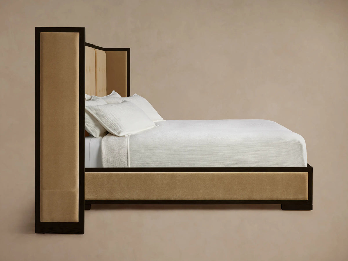 Corner of Darien Extended Box-Tufted Shelter Bed. Dark oak frame with light beige box-tufted upholstered panels.
