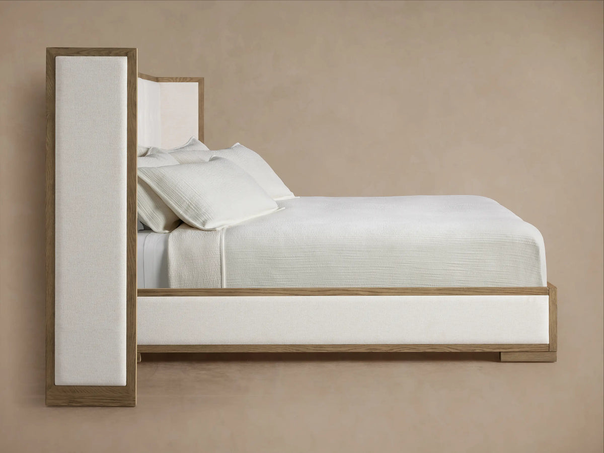 Close-up of Darien Extended Box-Tufted Shelter Bed. Light oak frame with visible grain, off-white box-tufted upholstered panel.