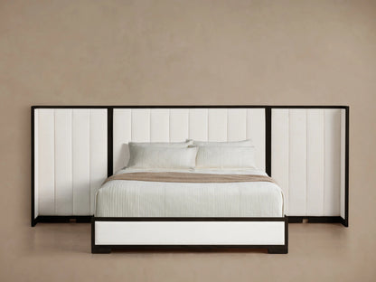 Extended Channel-Stitched Shelter Bed: tall black-framed, white upholstered headboard & base, white bedding on wood floor.