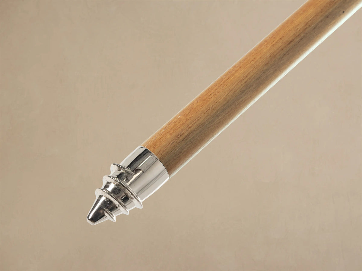 Close-up of the cream umbrella canopy with a silver finial and decorative cream fringe along the edges.