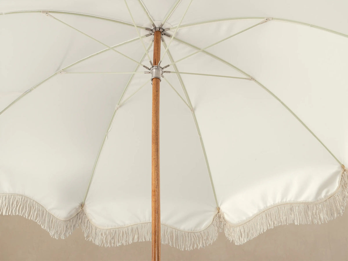 Close-up of a white square stand base with four silver circular feet, supporting a white vertical column, topped with a brown wooden rod.