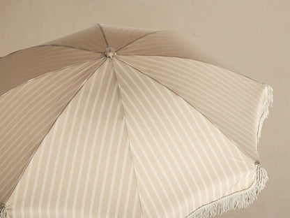 Overhead close-up view of a beige and white striped umbrella canopy with a silver finial and fringe trim.