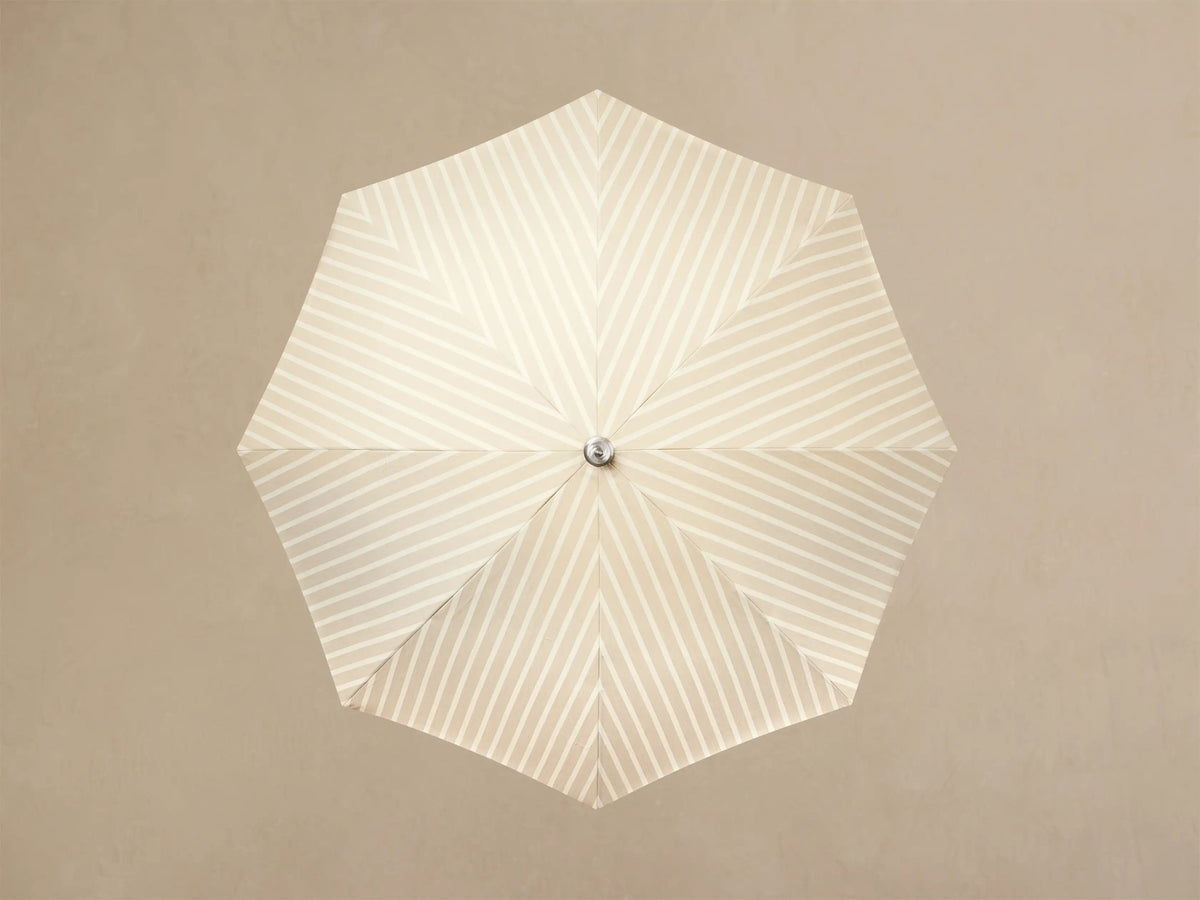 Front view of a cream and white striped parasol with a cream fringe and a light wood pole.