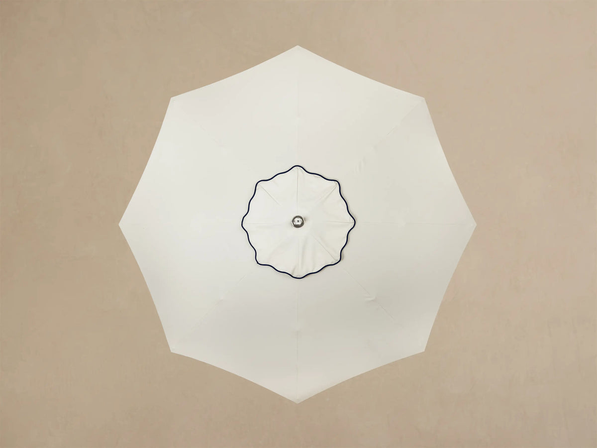 Front view of a white round base with a ruffled, pleated edge, small silver feet, supporting a cream column and a wooden rod.