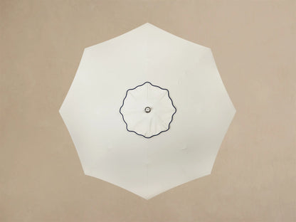 Front view of a white round base with a ruffled, pleated edge, small silver feet, supporting a cream column and a wooden rod.