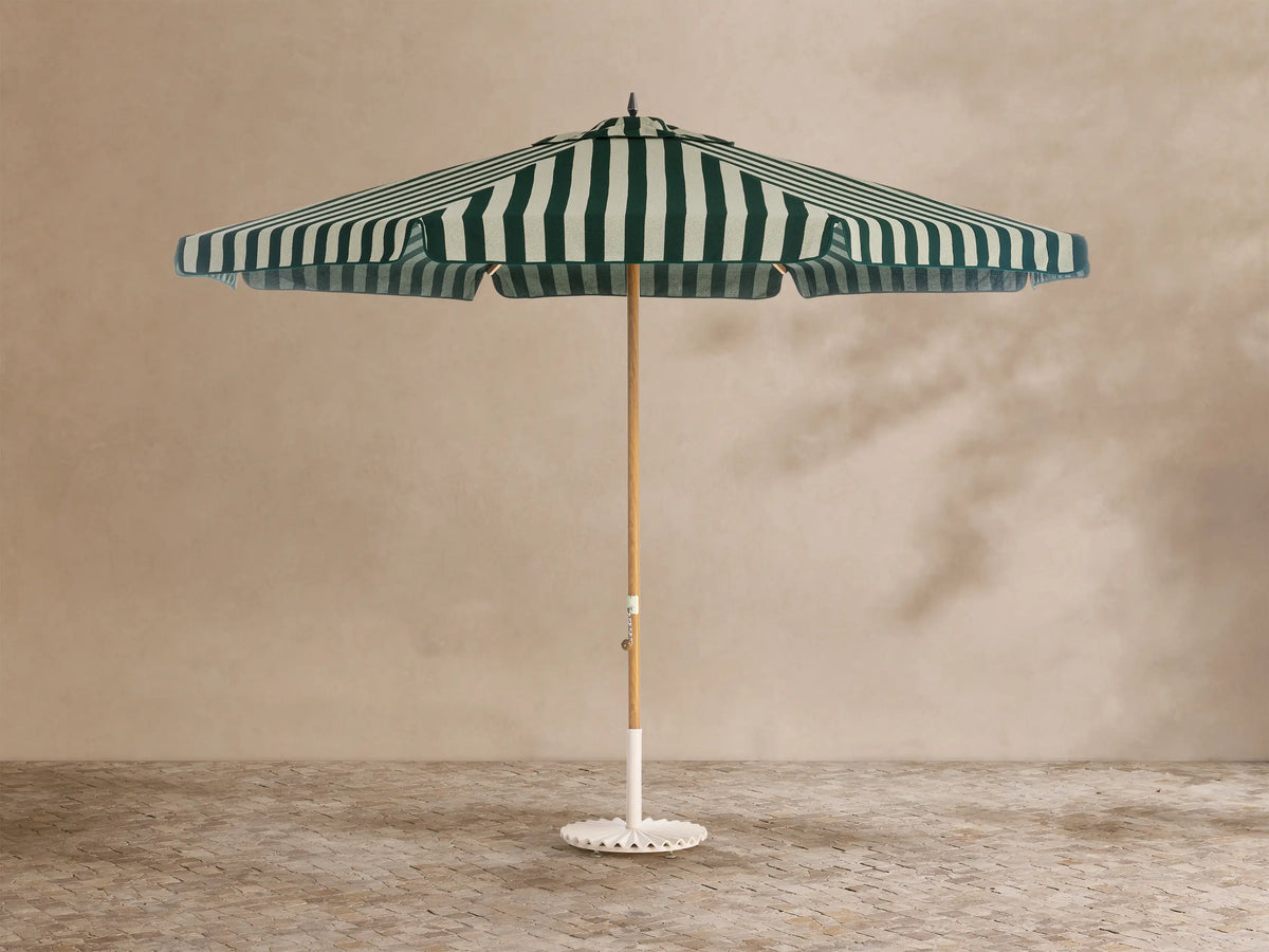 Front view of a patio umbrella with a green and white striped scalloped canopy, wooden pole, and white decorative base.