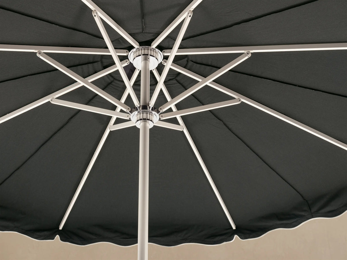 Front view of a black patio umbrella with a scalloped edge and white trim, standing upright with a white pole and round base.