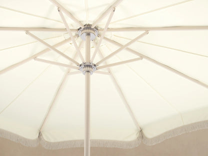 Front view of a Cream patio umbrella with a scalloped canopy edge and white fringe, on a white pole and round base.