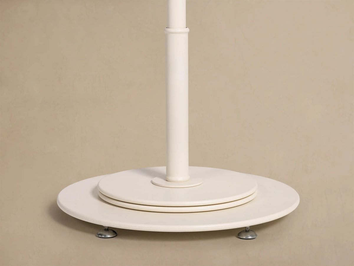 Top view of a cream and black striped umbrella canopy with varied stripe directions, a ruffled center, and scalloped black piping.