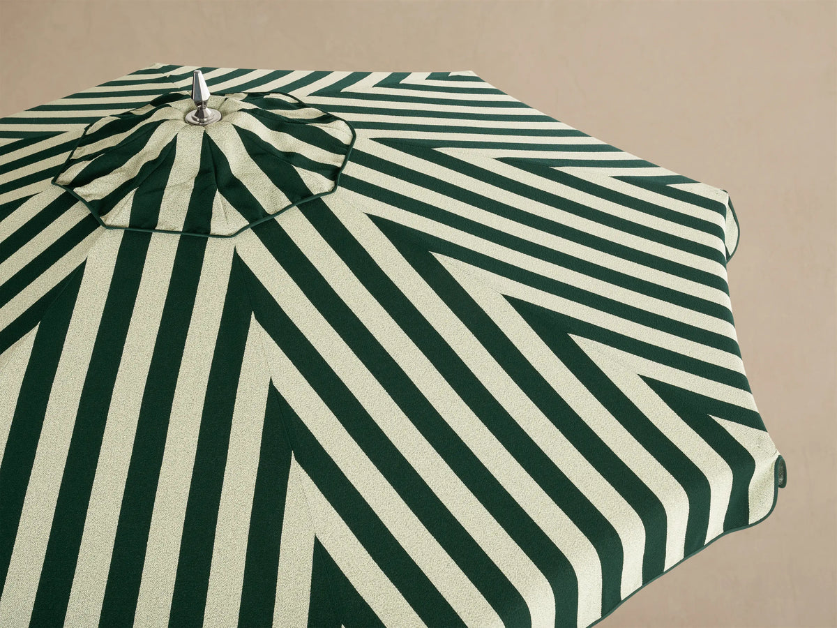 Interior view of an open dark green and light green striped umbrella, showing its white support frame and central pole.