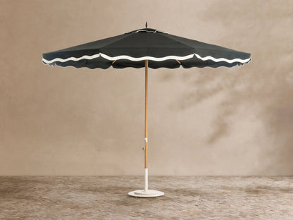 Front view of a black outdoor umbrella with white scalloped trim, a light wood pole, and a white base.