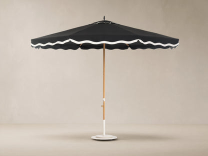 Front view of a black outdoor umbrella with white scalloped trim, a light wood pole, and a white base.