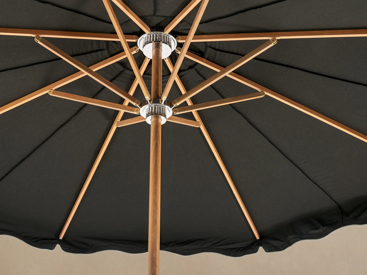 Front view of a black outdoor umbrella with white scalloped trim, a light wood pole, and a white base.