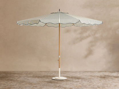 Front view of a cream and black striped patio umbrella with a scalloped edge, wooden pole, and white base.