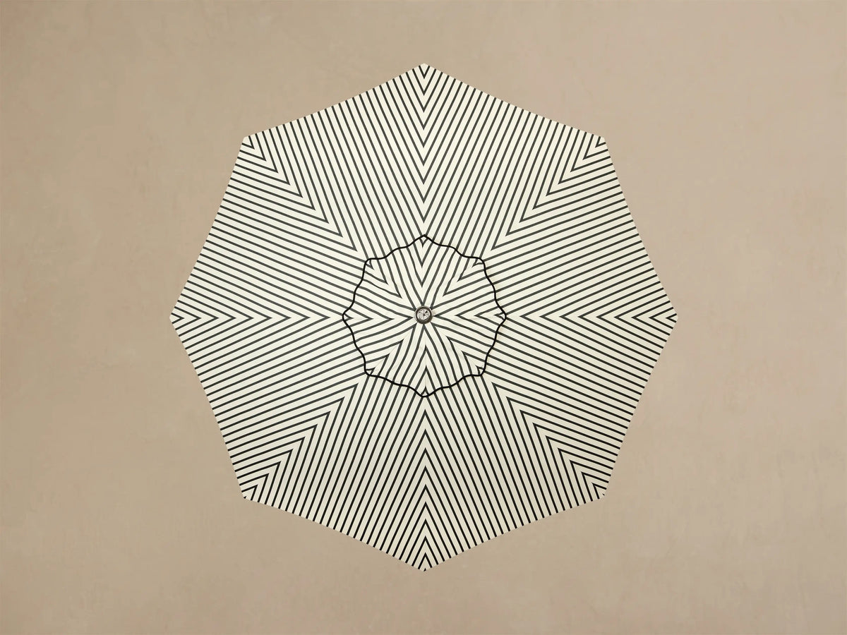Close-up of the off-white round umbrella base with concentric rings, a cylindrical pole, and silver adjustable feet.