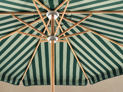 Front view of an outdoor patio umbrella with forest green and off-white vertical stripes, a natural wood pole, and a round white base.